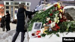 Жена полага цветя на паметника на жертвите на политическите репресии след смъртта на руския опозиционен лидер Алексей Навални, в Москва, Русия, 16 февруари 2024 г.