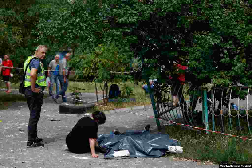 O femeie stă lângă trupurile rudelor ei ucise. 