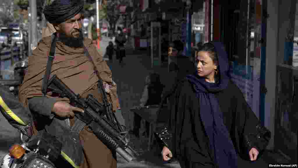 A Taliban fighter and an Afghan woman eye one another in Kabul in December 2022. Since their return to power in August 2021, the hard-line Islamists have waged a brutal crackdown on dissent and reintroduced their extreme and tribal interpretation of Islamic Shari’a law.