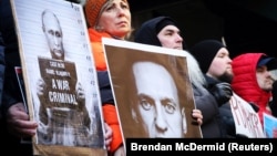 Manifestanții țin în brațe imagini cu Vladimir Putin în care președintele rus numit „criminal de război” și cu Alexei Navalnîi la un miting lângă consulatul Rusiei din New York, după anunțul morții opozantului rus.