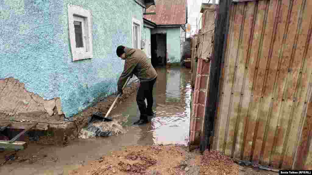 A villager clears muck near his home in Koyandy, a village some 20 kilometers northeast of the nation's capital, Astana. Residents of Koyandy took to the streets and barricaded the roads, furious at the authorities' inability to prepare for the seasonal floods. 