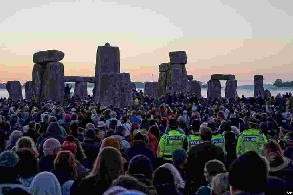 Policajci stoje među ljudima koji slave izlazak sunca u Stonehengeu, blizu Amesburyja, u Wiltshireu, u južnoj Engleskoj, 21. juna 2024., tokom festivala ljetnog solsticija, koji datira hiljadama godina unazad, slaveći najduži dan u godini. Kameni spomenik - isklesan i izgrađen u vrijeme kada nije bilo metalnog alata - simbolizira britanski polu-mitski predistorijski period i iznjedrio je bezbroj legendi. 
