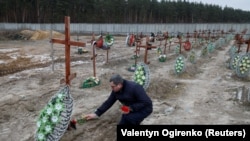Буча шаарынын мэри орус күчтөрү убактылуу басып алган маалда өлтүрүлгөн жергиликтүү тургундардын мүрзөлөрүнө гүл коюп жатат. 12-февраль, 2023-жыл. Украина.
