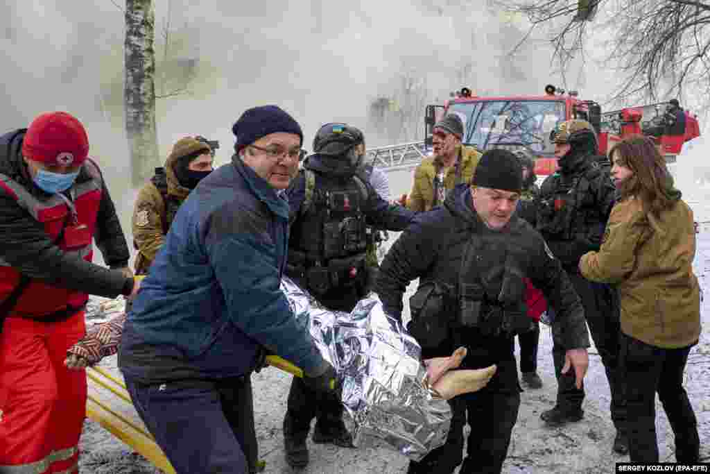 З пошкодженого та тліючого житлового будинку рятувальники виносять травмовану жінку, Харків, 23 січня 2024 року