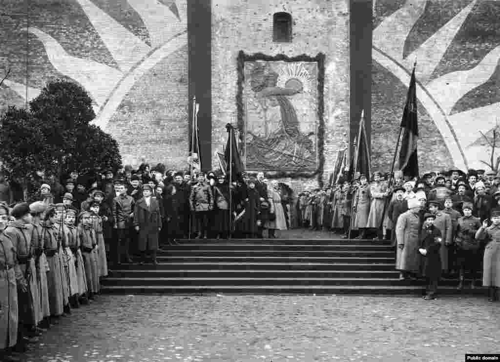 Boljševici na otvaranju spomen-reljefa na zidinama Kremlja. U godinama neposredno nakon Oktobarske revolucije 1917., na mjestu današnjeg mauzoleja nalazio se ovaj bareljef u spomen na komuniste koji su ubijeni u revoluciji 1917. i pokopani u masovnim grobnicama podno zidina Kremlja. Na ovoj fotografiji iz novembra 1918. Vladimir Lenjin (u sredini lijevo, dodiruje kapu) stoji gotovo na tačnom mjestu gdje će nekoliko godina kasnije biti postavljeno njegovo balzamirano tijelo.