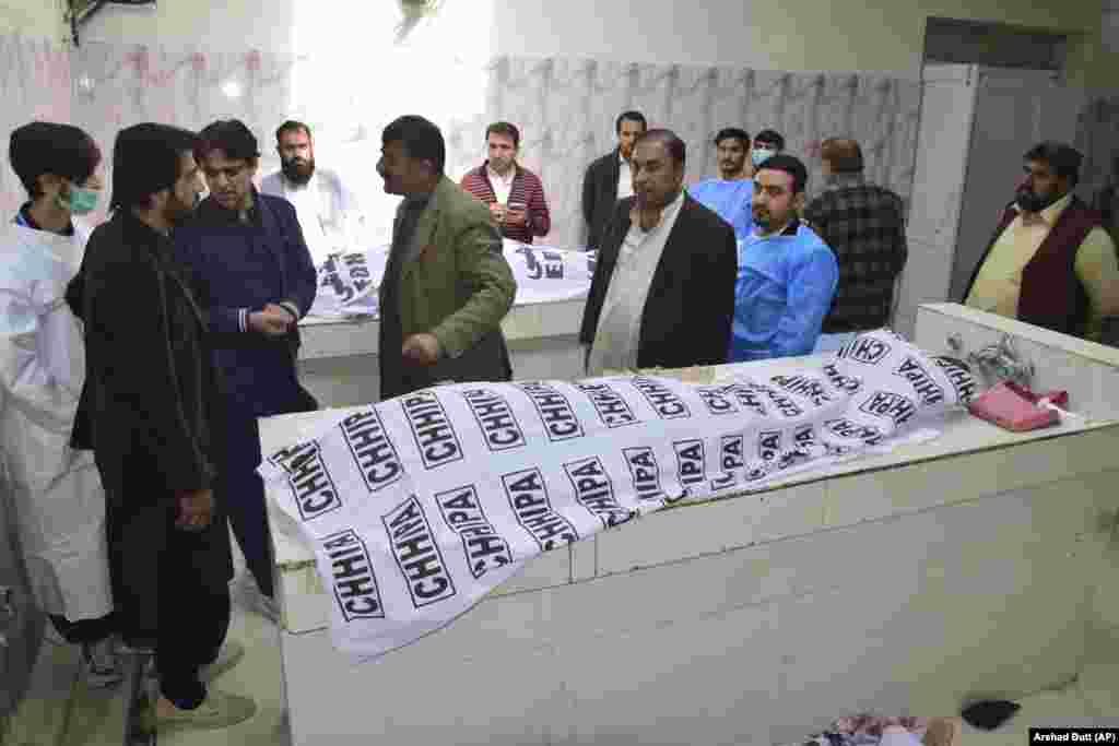 People gather around the bodies of victims waiting to be identified at the hospital in Quetta. 