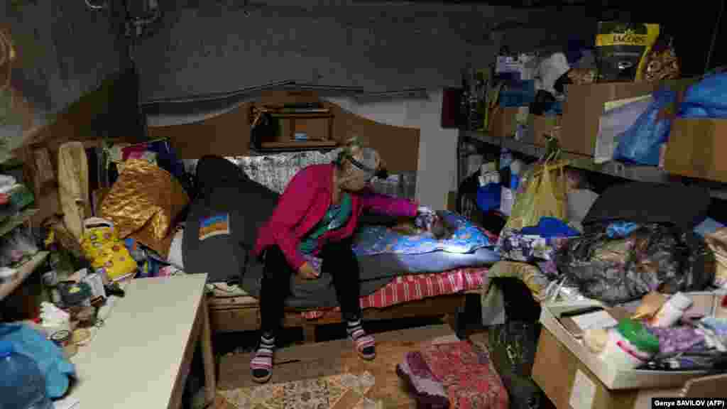A woman who did not wish to provide her name pets a dog in the cold, dark cellar where she lives.