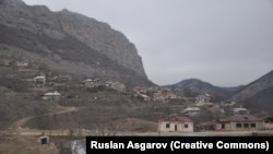 Дупки от куршуми по фасадата на училището в селото (на преден план) през декември 2021 г.