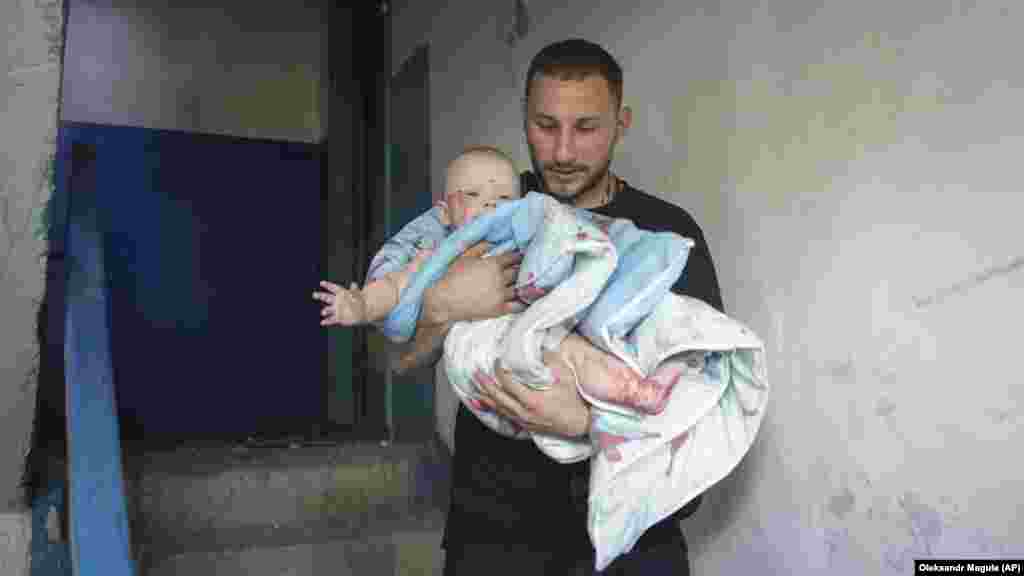 Muškarac nosi ozlijeđenu bebu nakon raketnog udara. Reuters je izvijestio da je najmlađe ozlijeđeno tromjesečno dijete. Stanje djeteta nije odmah bilo poznato nakon što je fotografija snimljena.