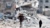Palestinci prolaze pored kuća koje su uništene u izraelskom napadu, Kan Junis, jug Pojasa Gaze, 22. maja 2024.