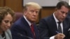  În timpul procedurii de trimitere în judecată, Donald Trump pare îngândurat și privește meditativ mai degrabă prin obiectivul aparatului de fotografiat decât către acesta.