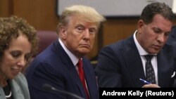  În timpul procedurii de trimitere în judecată, Donald Trump pare îngândurat și privește meditativ mai degrabă prin obiectivul aparatului de fotografiat decât către acesta.