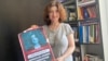 Novinarka Nino Zuriašvili sa plakatom na kojoj je njena fotografija i natpis "U Gruziji nema mjesta za agente"