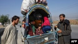 Afghan nationals along with their families stand along a road west of Peshawar, Pakistan, on October 6.