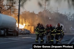 Firefighters transport a person away from the fire at the Crevedia gas filling station on August 26.