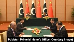 Pakistan's interim prime minister, Anwaar-ul Haq Kakar (back left), and his Chinese counterpart, Li Qiang (back right), look on as officials of both states signing agreements as part of the China-Pakistan Economic Corridor in Beijing on October 18.