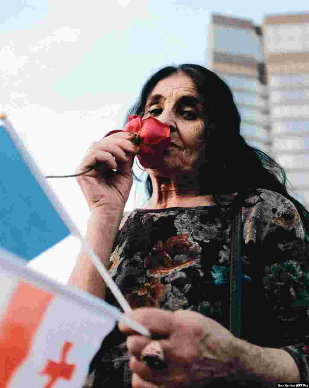 O altă protestatară miroase un trandafir în timp ce participă la miting.