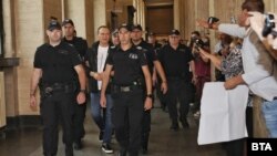 Съдебната охрана води Васил Божков в Софийския апелативен съд във вторник, докато негови поддръжници го аплодират.