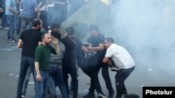 Armenia - Men help a fellow protester injured in a stun grenade blast, June 12, 2024.