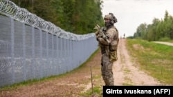 Un membru al Gărzii de Frontieră de Stat (SBG) patrulează de-a lungul gardului de la granița dintre Letonia și Belarus, în apropiere de Krivanda, în estul Letoniei, pe 8 august 2023, în timpul unei vizite a președintelui Letoniei în zonă.
