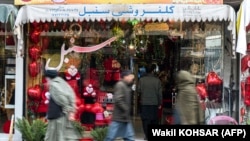 Afghan men walk past a gift shop along Flower Street in the Shar-e Naw area of Kabul on February 14.