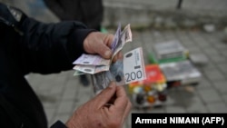 Ulični prodavac pokazuje novčanice srpskih dinara u gradu Gračanici, centralno Kosovo, 1. marta 2024.