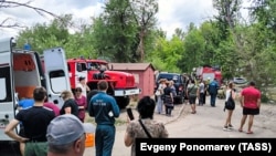 Ракеталык чабуулдан жабыркаган имараттын жанында топтолгон жергиликтүүлөр. 7-июнь, 2024-жыл. 