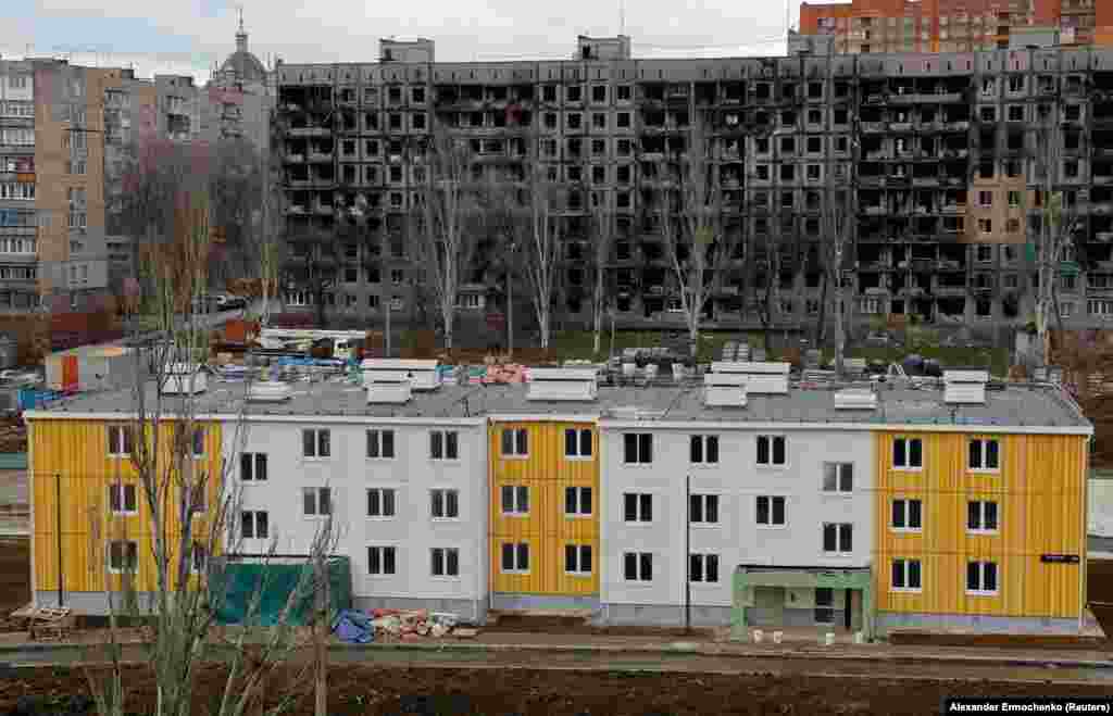 Nova zgrada ispred ratom razrušenog stambenog bloka. Istraživački tim opozicionog političara Alekseja Navaljnog tvrdi da najviši ruski zvaničnici lično profitiraju od projekata rekonstrukcije koji su u toku u Mariupolju. 