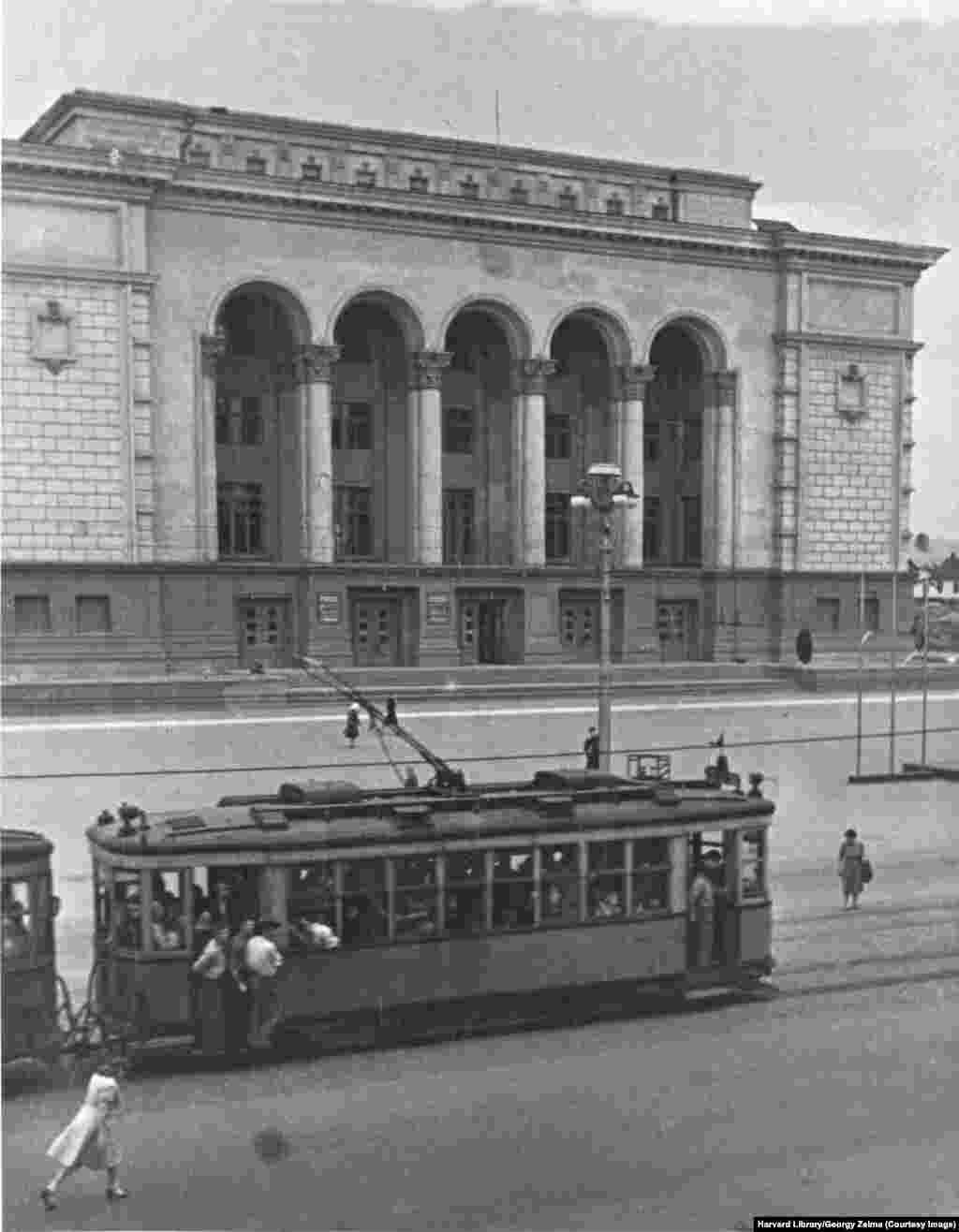 Un tramvai trece prin fața Teatrului Donețk, care se chema la acel moment Teatrul Dramatic Stalino. Teatrul a intrat în 2014 în atenția lumii pentru că a vrut să respecte programul reprezentațiilor în ciuda tulburărilor susținute de Rusia care începuseră în oraș.