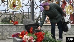A woman lays flowers at a memorial near the train station in Kramatorsk in Ukraine's Donetsk region where dozens of civilians were killed by a Russian missile strike one year ago.