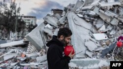 38 жаштагы Огун Север Окур жер титирөөдө набыт болгон балдарынын акыркы оюнчуктарын - шарларды үйлөөдө. Антакия шаары, Түркия. Февраль, 2023-жыл.