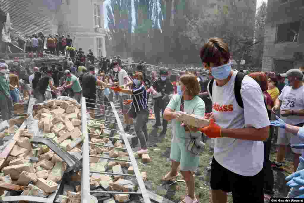 Cetățenii Kievului s-au strâns în curtea spitalului și ajută la înlăturarea molozului. 