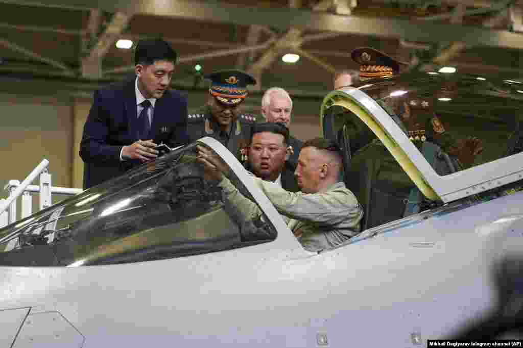 Liderul nord-coreean Kim Jong Un, în centru, se uită la cabina unui avion militar de vânătoare Su-57, la o uzină aeronautică rusă din Komsomolsk-pe-Amur, la aproximativ 6.200 de kilometri est de Moscova, în Rusia. Fotografie difuzată vineri dimineață de guvernatorul regiunii Habarovski Krai, Mihail Degtiarev, pe canalul său de Telegram.