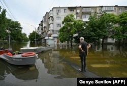 Місцевий житель дивиться на затоплену вулицю в Херсоні, 10 червня 2023 року