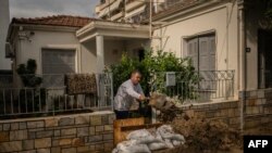 Местен жител почиства входа на къщата си след бурята "Елиас" във Волос