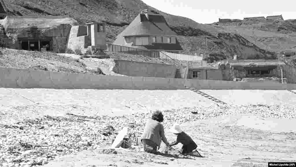 Francuska djeca se igraju na plaži u Vierville-dur-Mer-u-poznatoj kao Omaha Beach- gdje još uvijek stoje njemački bunkeri 6. juna 1964., 20 godina nakon iskrcavanja na dan D. Tokom 11 godina na funkciji predsjednika Francuske, Charles de Gaulle je odbijao da učestvuje u događajima za Dan D. "Odbio je da obilježava 6. jun, s obzirom na način na koji su ga tretirali u vrijeme iskrcavanja na Dan D. Nije bio uključen u rasprave niti u provedbu plana”, kaže istoričar Denis Peschanski. De Gaulle također nije pozvao svjetske lidere na 25. godišnjicu 1969. godine.