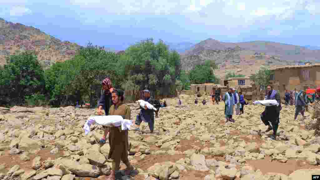 People carry the bodies of children who died in flash floods in Afghanistan's central Maidan Wardak Province on July 23. Over the past three days, seasonal rains caused flooding that killed at least 31 people and left dozens missing.