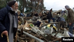 Un palestinian (stânga) se uită la rămășițele casei sale după ce aceasta a fost distrusă împreună cu alte cinci case de un buldozer israelian, în apropierea așezării evreiești Netzareem din sudul Fâșiei Gaza, 4 februarie 2001.