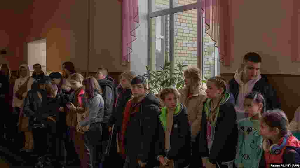 Діти збираються перед евакуацією, Херсон, 30 жовтня 2023 року. Надія Кондраткова, мати двох доньок, яка вперше розлучається зі своїми дітьми, тремтіла від страху, а її очі наповнилися слізьми. «Їм потрібно відпочити подалі від вибухів і сирен», – пояснила Кондраткова своє рішення відправити своїх доньок з Херсону. «Вони виснажені – каже вона. – Вони вже не можуть спати і кричать ночами»