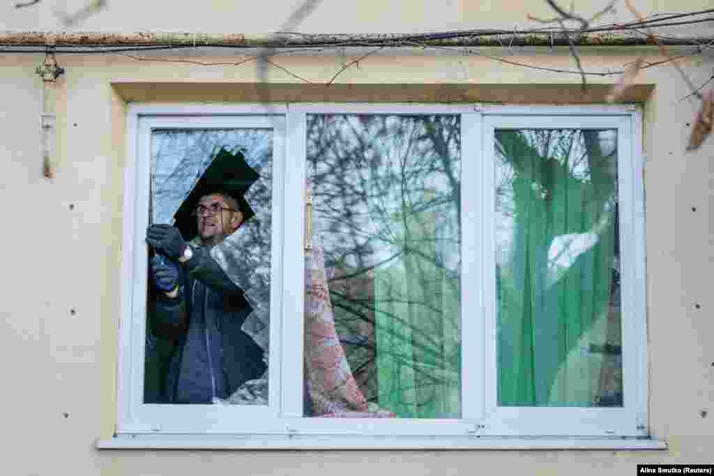 Місцевий житель виймає бите скло з вікна своєї квартири, яке було пошкоджене під час атаки. Попри докази і свідчення, Москва від початку повномасштабного вторгнення заперечує цілеспрямовану атаку на цивільних.