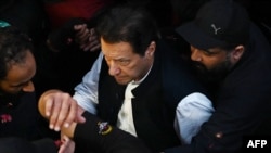 Security personnel escort former Pakistani Prime Minister Imran Khan as he arrives at the high court in Lahore on March 17.