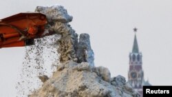 Мръсен сняг се сипе от транспортната лента на камион в мразовит ден в Москва. Спаската кула на Кремъл е на заден план. Москва, Русия, 7 декември 2023 г. 