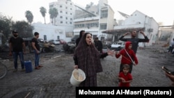 د غزې الاهلي عرب ويجاړ شوي روغتون مخې ته فلسطینۍ کورنۍ ولاړې دي