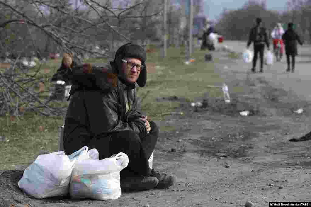 Житель сидит на обочине дороги в Мариуполе