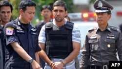 Thai police officers with detainee Mohammad Kharzei (center), one of three Iranian suspects held in a bomb investigation.