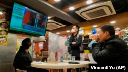 Oamenii dintr-un restaurant din Hong Kong urmăresc o emisiune în timp ce trupele ruse invadează Ucraina pe 24 februarie 2022.
