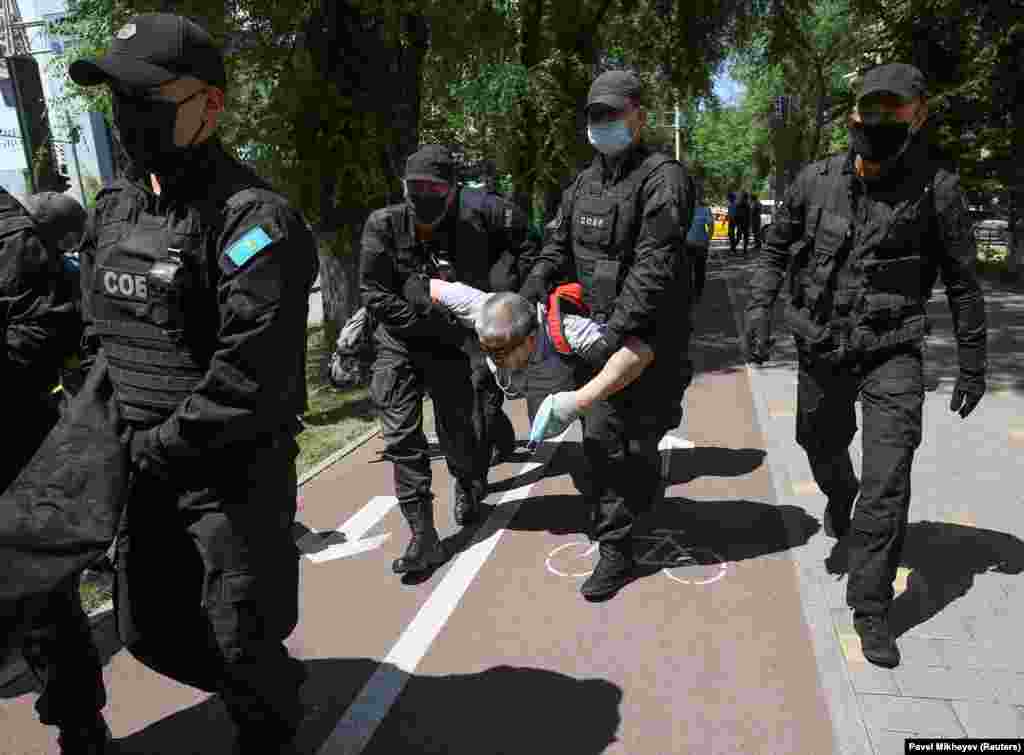 Акцияга чыккандардын бирин полиция кармап баратат. 