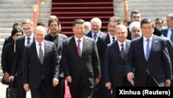 Си Цзинпин жана Шанхай кызматташтык уюмуна (ШКУ) байкоо салган башка мамлекеттердин лидерлери, аймактык жана эл аралык уюмдардын өкүлдөрү ШКУ кеӊешинин Бишкектеги 19-отурумунда сүрөткө түшүп жатат. Кыргызстан, 2019-жыл, 14-июнь.