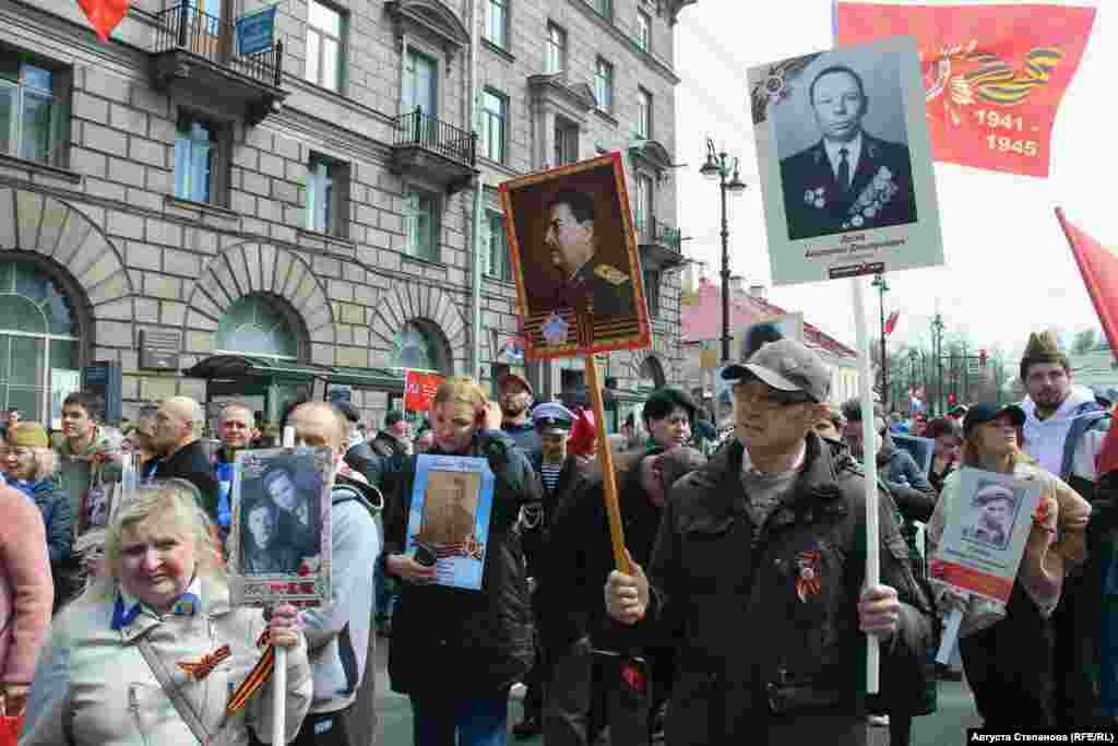 Участник акции "Бессмертный полк" в Петербурге с изображением своего родственника в одной руке и фотографией Иосифа Сталина в другой 