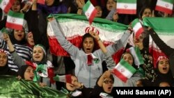 Iranian women cheer as they wave their country's flag after the authorities allowed a select group of women into Azadi Stadium to watch a friendly soccer match between Iran and Bolivia in Tehran on October 16, 2018.